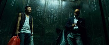 Movie still from “Transformers: Age of Extinction” (2014), directed by Michael Bay – A man and a woman sitting on a bench in front of a wall with writing on it; Medium shot, Low angle