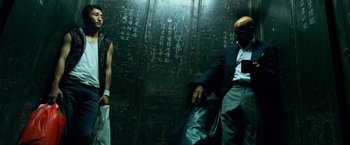 Movie still from “Transformers: Age of Extinction” (2014), directed by Michael Bay – A man and a woman standing next to each other in front of a wall; Medium shot, Low angle