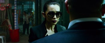 Movie still from “Transformers: Age of Extinction” (2014), directed by Michael Bay – A woman wearing a suit and sunglasses looking at a man in a suit; Close Up shot, Over the shoulder angle