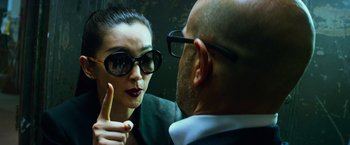 Movie still from “Transformers: Age of Extinction” (2014), directed by Michael Bay – A woman wearing sunglasses talking to a man wearing a suit; Close Up shot, Over the shoulder angle