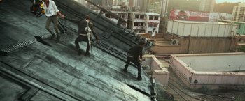 Movie still from “Transformers: Age of Extinction” (2014), directed by Michael Bay – Two men are working on the roof of a building; Wide shot, Overhead angle