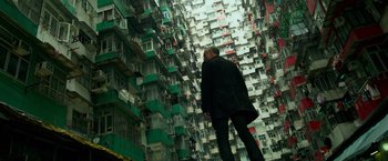 Movie still from “Transformers: Age of Extinction” (2014), directed by Michael Bay – A man standing in front of a tall building with lots of windows; Wide shot, Low angle