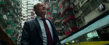 Movie still from “Transformers: Age of Extinction” (2014), directed by Michael Bay – A man in a suit and tie standing in front of a building; Medium shot, Low angle