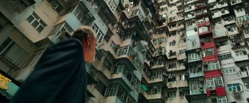 Movie still from “Transformers: Age of Extinction” (2014), directed by Michael Bay – A man standing in front of a tall building with lots of windows and balconies; Extreme Wide shot, Overhead angle