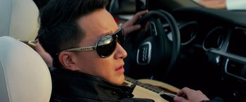 Movie still from “Transformers: Age of Extinction” (2014), directed by Michael Bay – A man wearing sunglasses sitting in a car with a guitar; Close Up shot, Over the shoulder angle