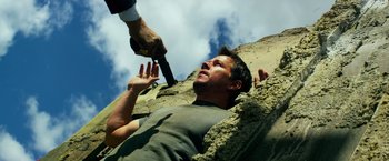 Movie still from “Transformers: Age of Extinction” (2014), directed by Michael Bay – A man on the ground being held up by a man with an umbrella; Close Up shot, Overhead angle