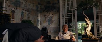 Movie still from “Transformers: Dark of the Moon” (2011), directed by Michael Bay – An older man sitting in front of a painting; Medium shot, Over the shoulder angle
