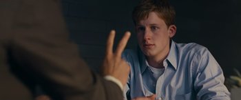 Movie still from “Transformers: Dark of the Moon” (2011), directed by Michael Bay – A young man sitting in front of a man with a peace sign in his hand; Close Up shot, Over the shoulder angle
