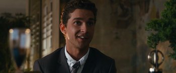 Movie still from “Transformers: Dark of the Moon” (2011), directed by Michael Bay – A man in a suit and tie smiling for the camera; Close Up shot, Over the shoulder angle