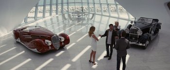 Movie still from “Transformers: Dark of the Moon” (2011), directed by Michael Bay – A group of people standing in front of a red car; Wide shot, High angle