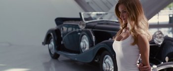 Movie still from “Transformers: Dark of the Moon” (2011), directed by Michael Bay – A woman standing in front of an antique car; Medium shot, Over the shoulder angle