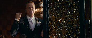 Movie still from “Transformers: Dark of the Moon” (2011), directed by Michael Bay – A man in a suit standing next to an iron gate; Medium shot, Over the shoulder angle