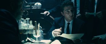 Movie still from “Transformers: Dark of the Moon” (2011), directed by Michael Bay – A man sitting at a table with a paper in his hand; Medium shot, Low angle