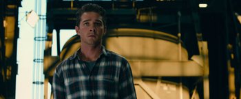 Movie still from “Transformers: Dark of the Moon” (2011), directed by Michael Bay – A man in a plaid shirt standing next to a wall; Close Up shot, Low angle