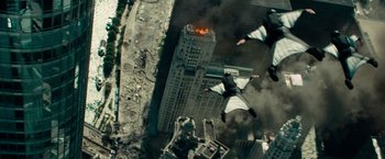 Movie still from “Transformers: Dark of the Moon” (2011), directed by Michael Bay – A group of people flying in the air near a building; Wide shot, Overhead angle