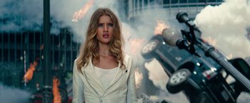 A woman standing in front of an exploding car