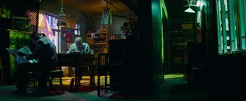 Movie still from “Transformers: Revenge of the Fallen” (2009), directed by Michael Bay – An older man sitting at a table in a dark room; Wide shot, High angle