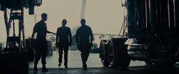 Movie still from “Transformers: Revenge of the Fallen” (2009), directed by Michael Bay – Two men in suits walking away from an airplane; Wide shot, Low angle