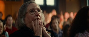 Movie still from “Transformers: Revenge of the Fallen” (2009), directed by Michael Bay – An older woman with glasses is holding her hands to her mouth; Close Up shot, Over the shoulder angle