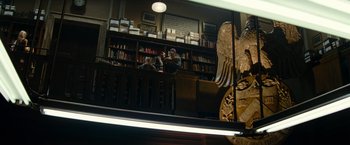 Movie still from “Transformers: Revenge of the Fallen” (2009), directed by Michael Bay – Two people sitting at a table in front of bookshelves; Wide shot, Low angle
