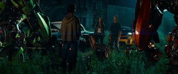 Movie still from “Transformers: Revenge of the Fallen” (2009), directed by Michael Bay – A group of people standing in the grass at night; Wide shot, Over the shoulder angle