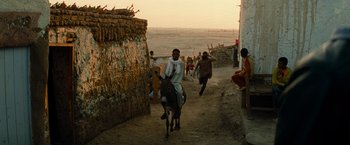 Movie still from “Transformers: Revenge of the Fallen” (2009), directed by Michael Bay – A man riding a donkey down a dirt road; Wide shot, Over the shoulder angle
