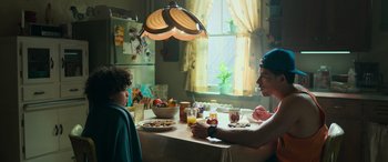 Movie still from “Transformers: Rise of the Beasts” (2023), directed by Steven Caple Jr. – Two people sitting at a table with a plate of food; Medium shot, Over the shoulder angle