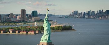 Movie still from “Transformers: Rise of the Beasts” (2023), directed by Steven Caple Jr. – The statue of liberty is seen from the air; Extreme Wide shot, Low angle