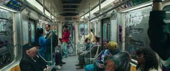 Movie still from “Transformers: Rise of the Beasts” (2023), directed by Steven Caple Jr. – A group of people riding on a subway train; Wide shot, High angle