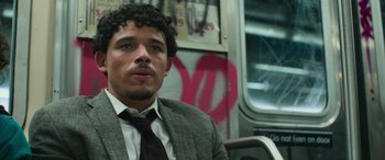 Movie still from “Transformers: Rise of the Beasts” (2023), directed by Steven Caple Jr. – A man in a suit and tie sitting on a bus; Close Up shot, Low angle