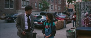 Movie still from “Transformers: Rise of the Beasts” (2023), directed by Steven Caple Jr. – A man and a boy standing on the side of the street; Medium shot, Over the shoulder angle