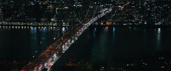 Movie still from “Transformers: Rise of the Beasts” (2023), directed by Steven Caple Jr. – An aerial view of a bridge at night with lights on it; Extreme Wide shot, High angle
