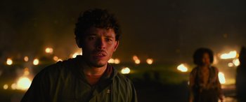Movie still from “Transformers: Rise of the Beasts” (2023), directed by Steven Caple Jr. – A young man is standing in the dark with lights in the background; Close Up shot, Low angle