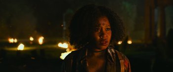 Movie still from “Transformers: Rise of the Beasts” (2023), directed by Steven Caple Jr. – A woman with a very long afro is standing in the dark; Close Up shot, Over the shoulder angle