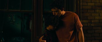 Movie still from “Transformers: Rise of the Beasts” (2023), directed by Steven Caple Jr. – A man and a boy are hugging in a dark room; Medium shot, Low angle