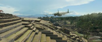 Movie still from “Transformers: Rise of the Beasts” (2023), directed by Steven Caple Jr. – An airplane is flying low over a field; Extreme Wide shot, High angle