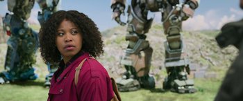 Movie still from “Transformers: Rise of the Beasts” (2023), directed by Steven Caple Jr. – A woman standing in front of a giant robot; Medium shot, Low angle