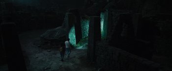 Movie still from “Transformers: Rise of the Beasts” (2023), directed by Steven Caple Jr. – Two people walking in a dark room with a light shining on them; Extreme Wide shot, High angle