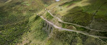 Movie still from “Transformers: Rise of the Beasts” (2023), directed by Steven Caple Jr. – An aerial view of a bridge on the side of a mountain; Extreme Wide shot, High angle