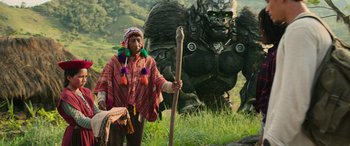 Movie still from “Transformers: Rise of the Beasts” (2023), directed by Steven Caple Jr. – An older woman standing in front of a giant creature; Wide shot, Low angle