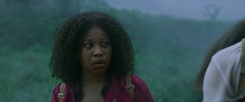 Movie still from “Transformers: Rise of the Beasts” (2023), directed by Steven Caple Jr. – A black woman with a bag in front of a forest; Close Up shot, Low angle