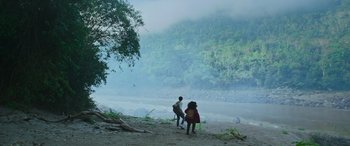 Movie still from “Transformers: Rise of the Beasts” (2023), directed by Steven Caple Jr. – Two people walking on a beach near a body of water; Extreme Wide shot, Low angle
