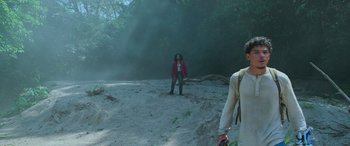 Movie still from “Transformers: Rise of the Beasts” (2023), directed by Steven Caple Jr. – Two people are standing in the dirt near a forest; Wide shot, Low angle