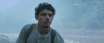 Movie still from “Transformers: Rise of the Beasts” (2023), directed by Steven Caple Jr. – A man with curly black hair and a white t - shirt; Close Up shot, Low angle