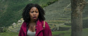 Movie still from “Transformers: Rise of the Beasts” (2023), directed by Steven Caple Jr. – A woman with a bruised face standing in front of an outdoor amphitheater; Close Up shot, Low angle