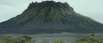 Movie still from “Transformers: Rise of the Beasts” (2023), directed by Steven Caple Jr. – A large mountain with a body of water in the middle of it; Extreme Wide shot, Low angle