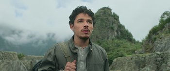 Movie still from “Transformers: Rise of the Beasts” (2023), directed by Steven Caple Jr. – A man with a backpack standing in front of a mountain; Close Up shot, Low angle