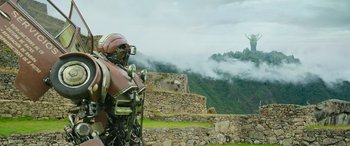 Movie still from “Transformers: Rise of the Beasts” (2023), directed by Steven Caple Jr. – A man in a helmet is standing in front of a stone wall; Extreme Wide shot, Low angle