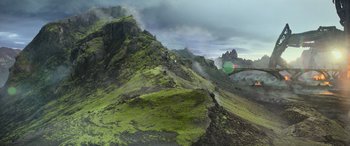 Movie still from “Transformers: Rise of the Beasts” (2023), directed by Steven Caple Jr. – A view of a mountain range with green grass on it's sides; Extreme Wide shot, High angle