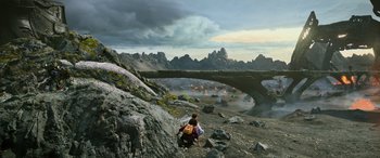 Movie still from “Transformers: Rise of the Beasts” (2023), directed by Steven Caple Jr. – A man is standing on a cliff looking at a bridge in the distance; Extreme Wide shot, High angle